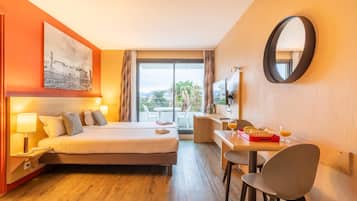 Hotellihuone, jossa on sänky, työpöytä, tuoli ja suuri ikkuna.