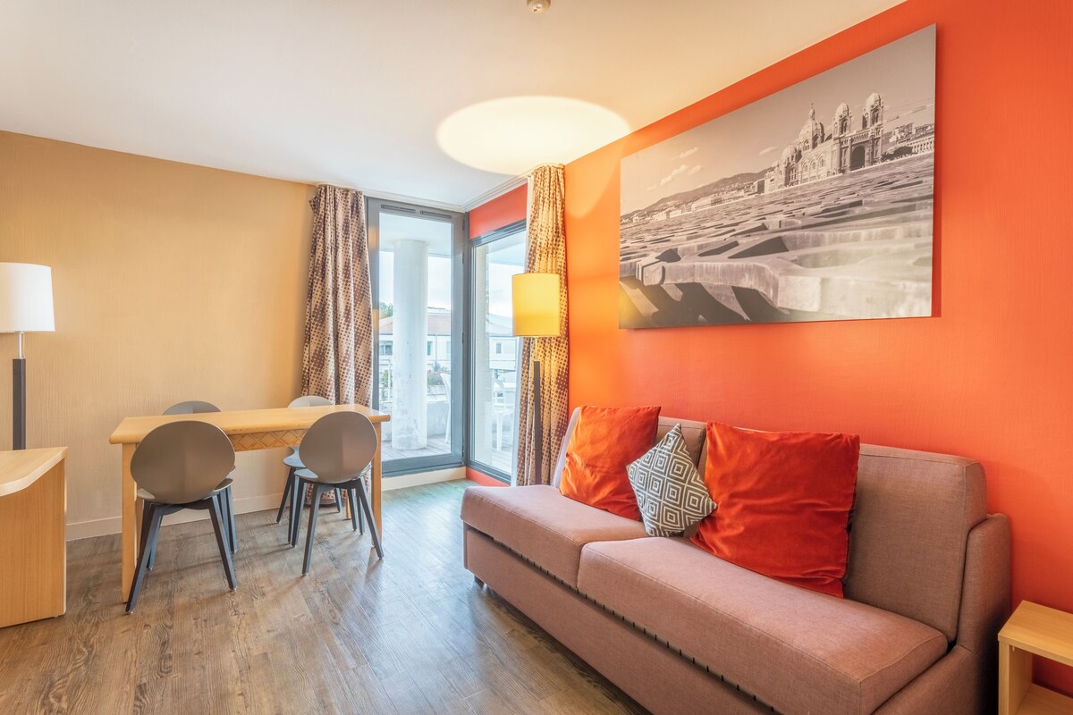 Une chambre d’hôtel moderne avec un coin repas, un canapé et une grande fenêtre.