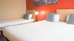 Une chambre d’hôtel avec deux lits simples, une table de chevet avec une lampe et un tableau accroché au mur.