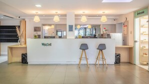 A reception area with a white counter, two grey bar stools, and pendant lighting.