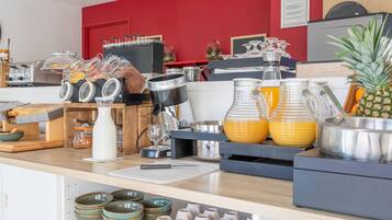 Un bufé de desayuno con diferentes opciones de comida, una máquina de café y una exhibición de frutas.