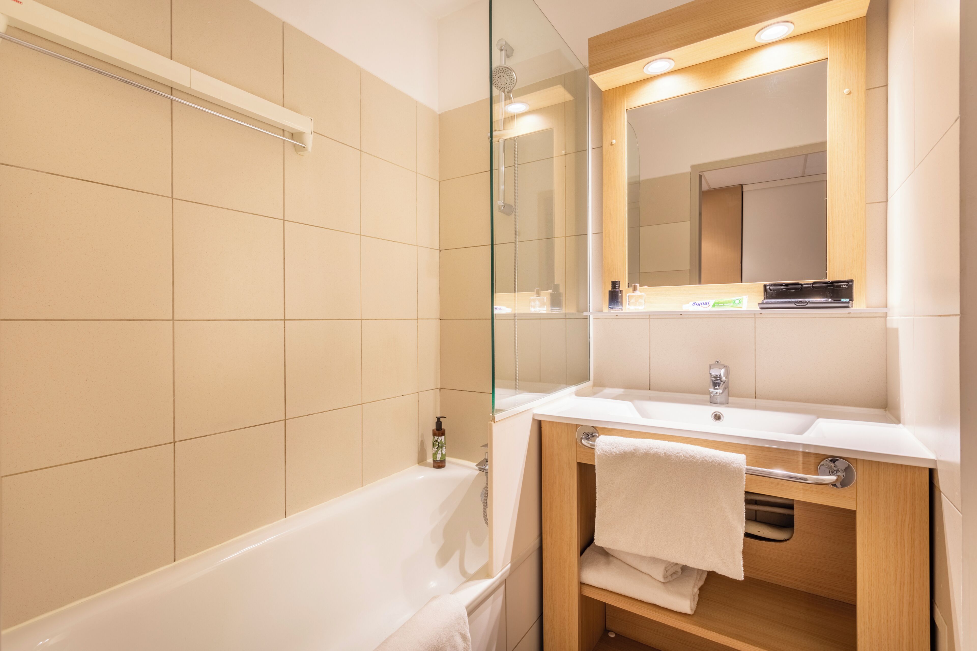 A modern bathroom with a bathtub, a sink, a mirror, and a towel rack.