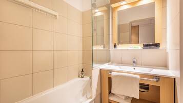A modern bathroom with a bathtub, a sink, a mirror, and a towel rack.