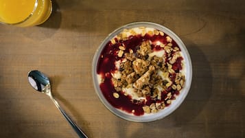 Een kom havermout met granola en fruit op een houten tafel.