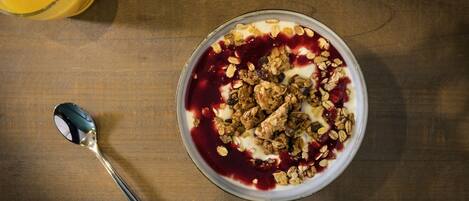 A bowl of cereal with granola and fruit on a wooden table.