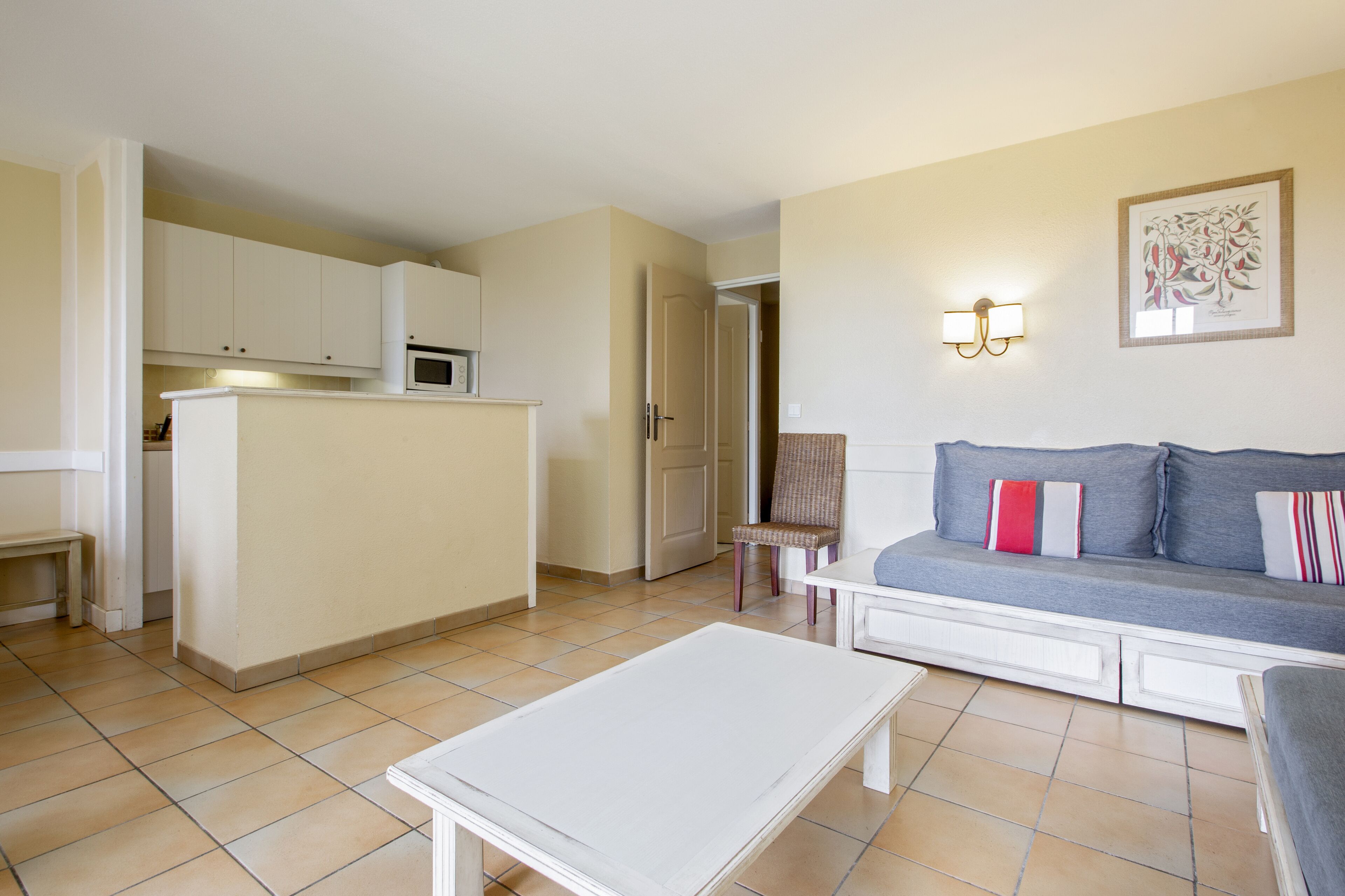 A compact living space with a kitchenette, a sofa with cushions, a chair, and a coffee table.