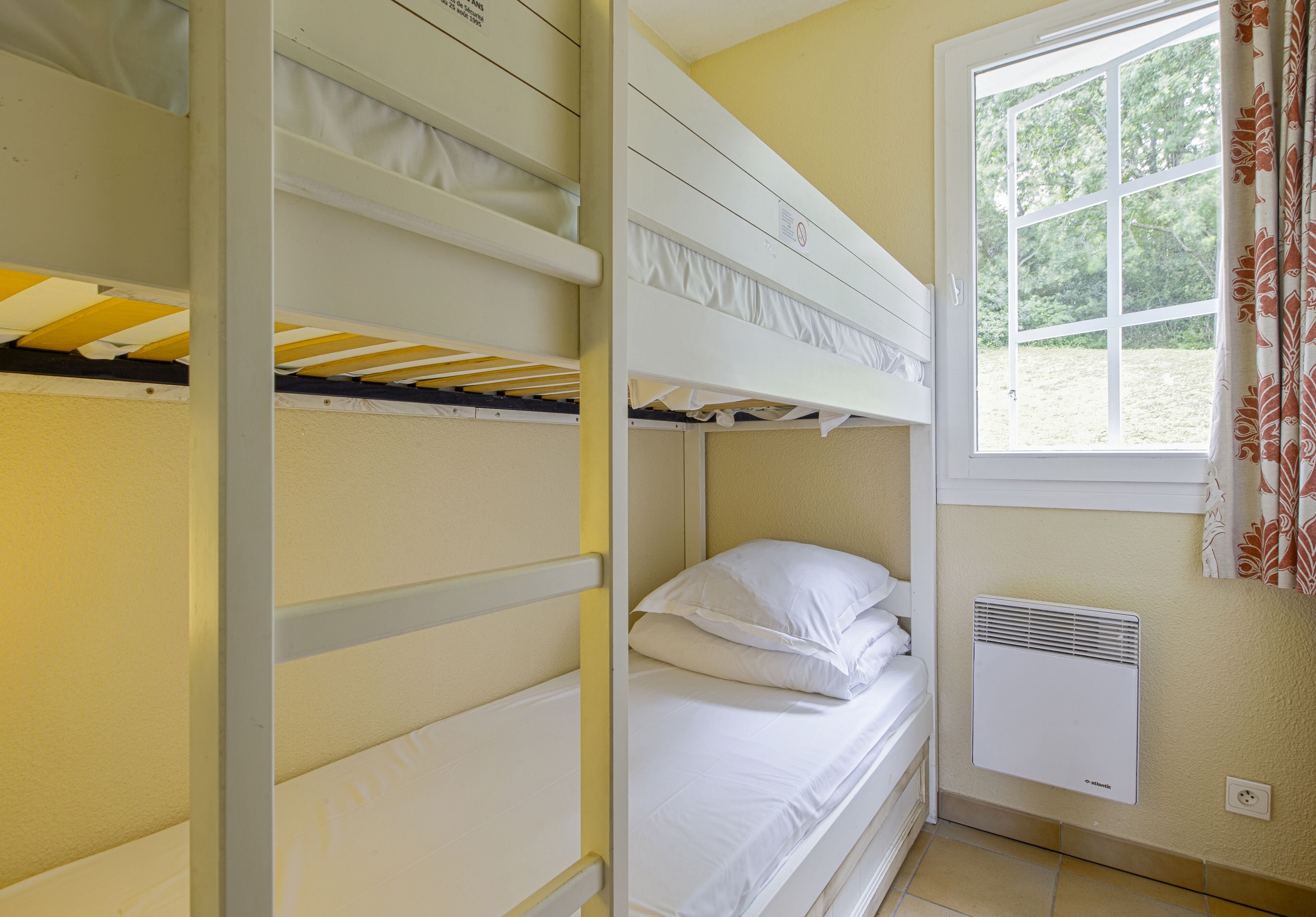 Dormitorio con literas, ventana y calentador en la pared.