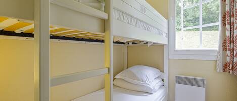 Dormitorio con literas, ventana y calentador en la pared.