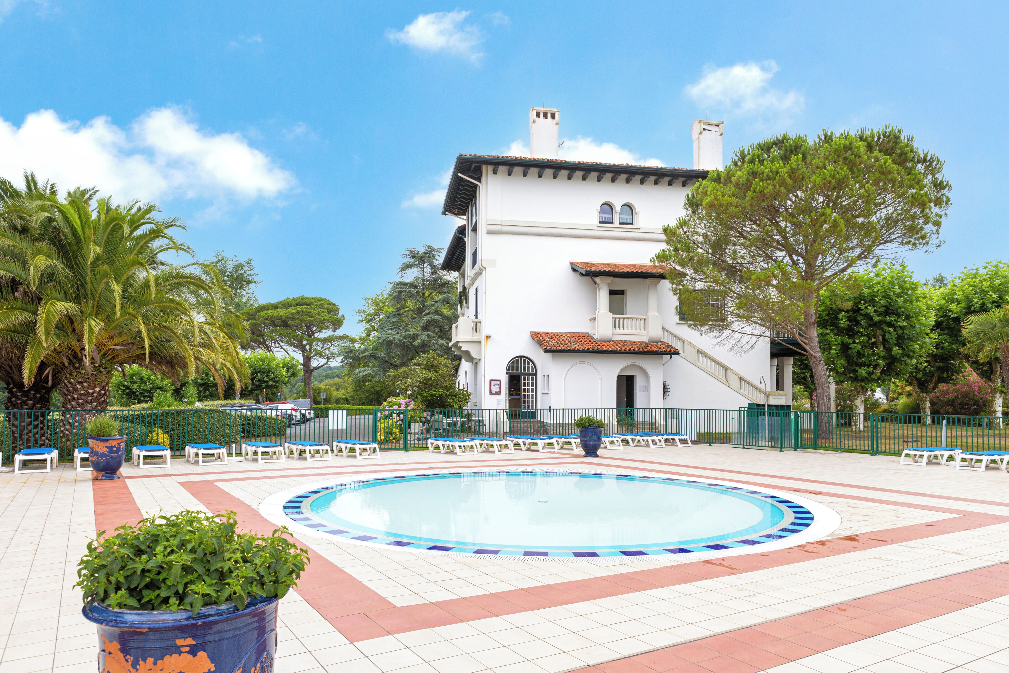 A pool area with lounge chairs and a building in the background.