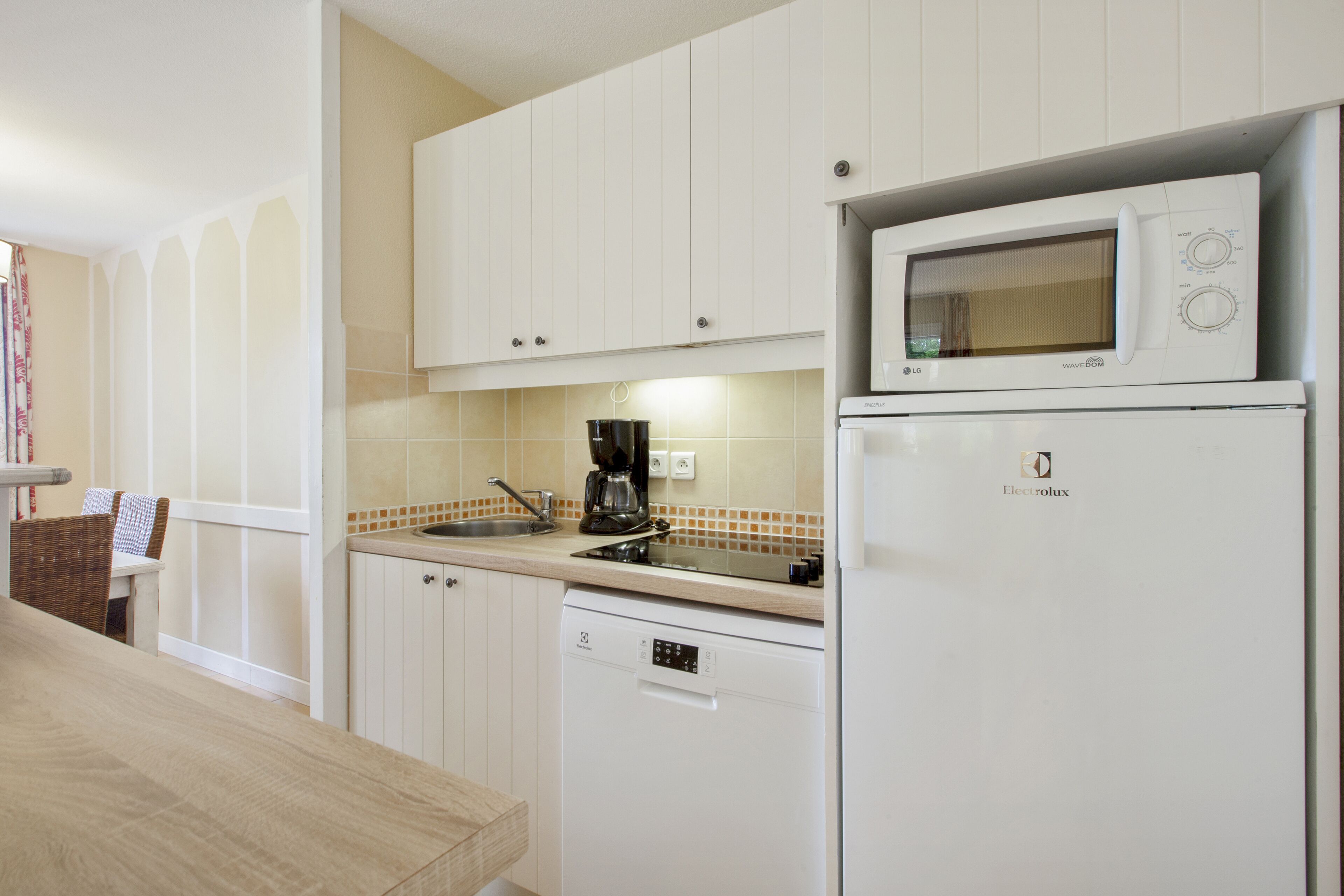 A kitchen with white cabinets, a microwave, a dishwasher, and a coffee maker.