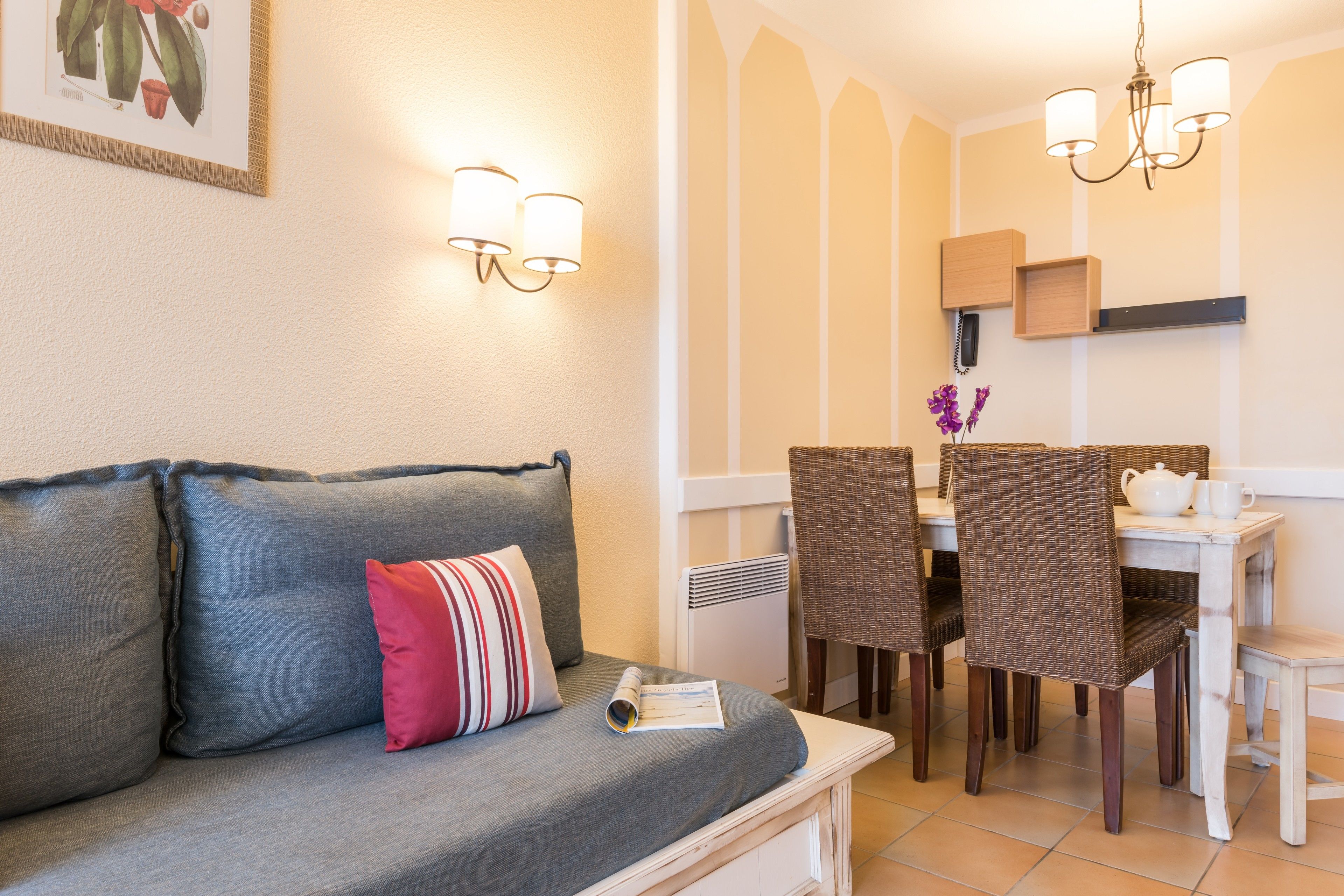 A cozy living area with a sofa, a dining table with chairs, and wall-mounted lighting.