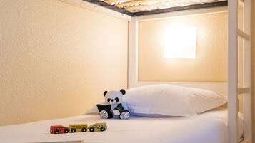 A bunk bed with a white mattress, a small bedside table, a lamp, and a toy panda.
