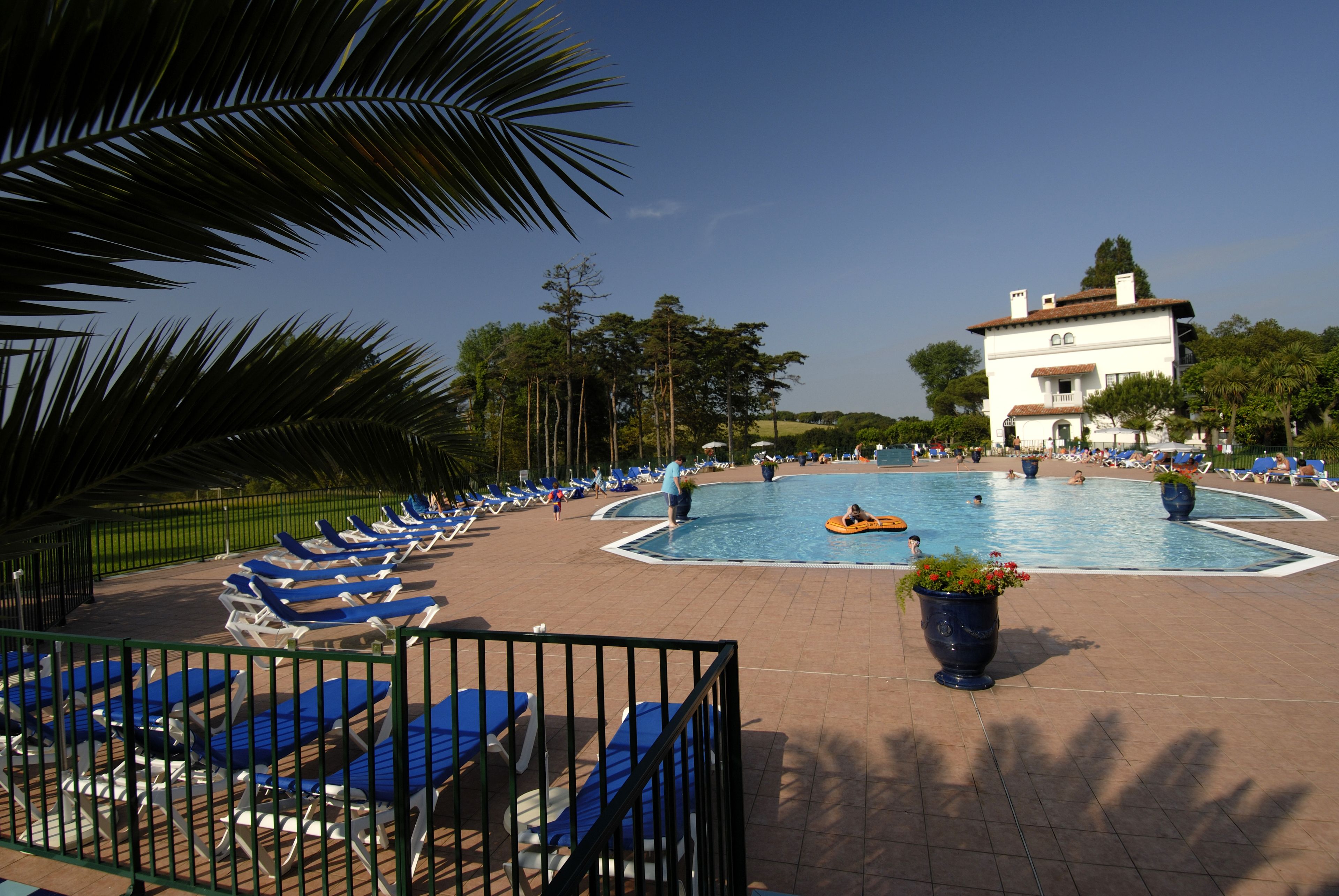 Un área de piscina con sillones reclinables y una piscina grande.