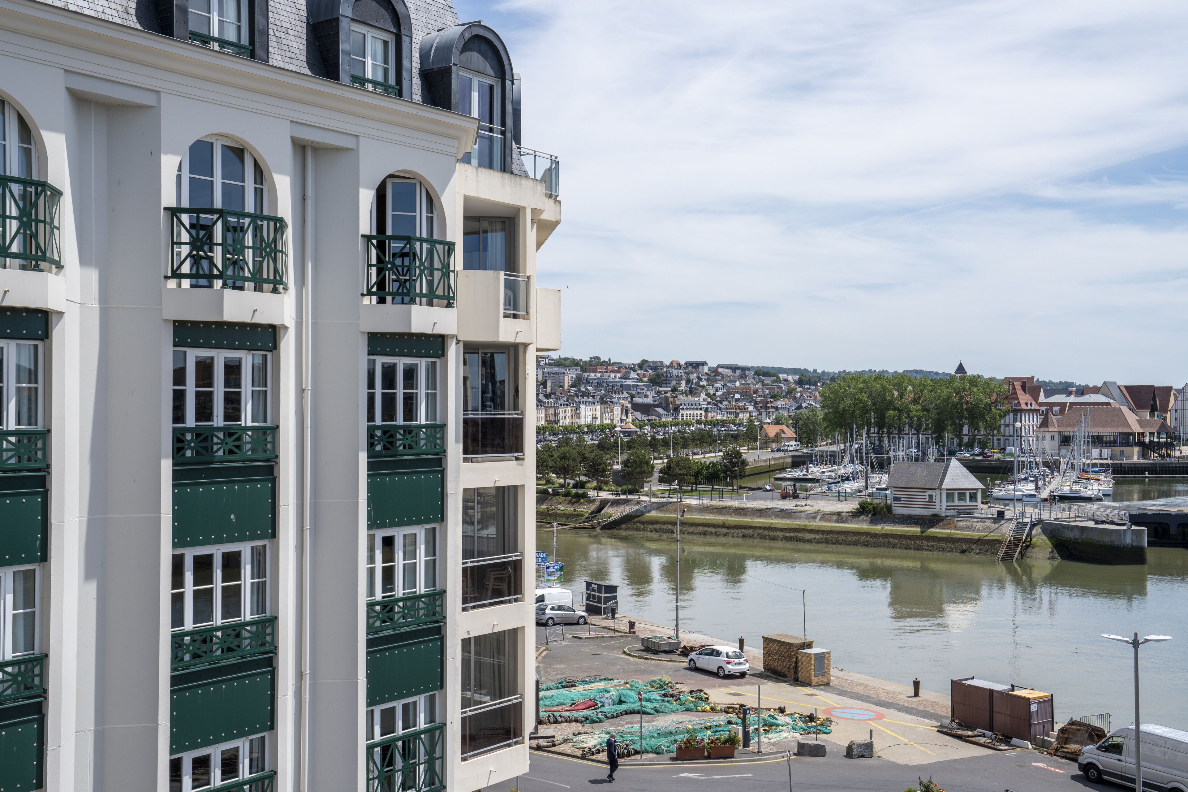 A multi-story building with balconies, a marina with boats, and a river view.