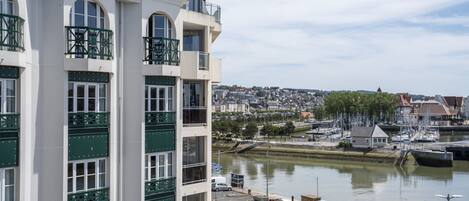 A multi-story building with balconies, a marina with boats, and a river view.