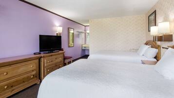 A hotel room with two beds, a TV, wooden dresser, and wall-mounted lamps.