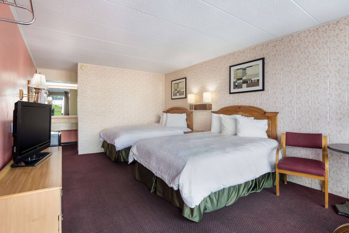 Een hotelkamer met twee bedden, een televisie, een stoel en een tafeltje.