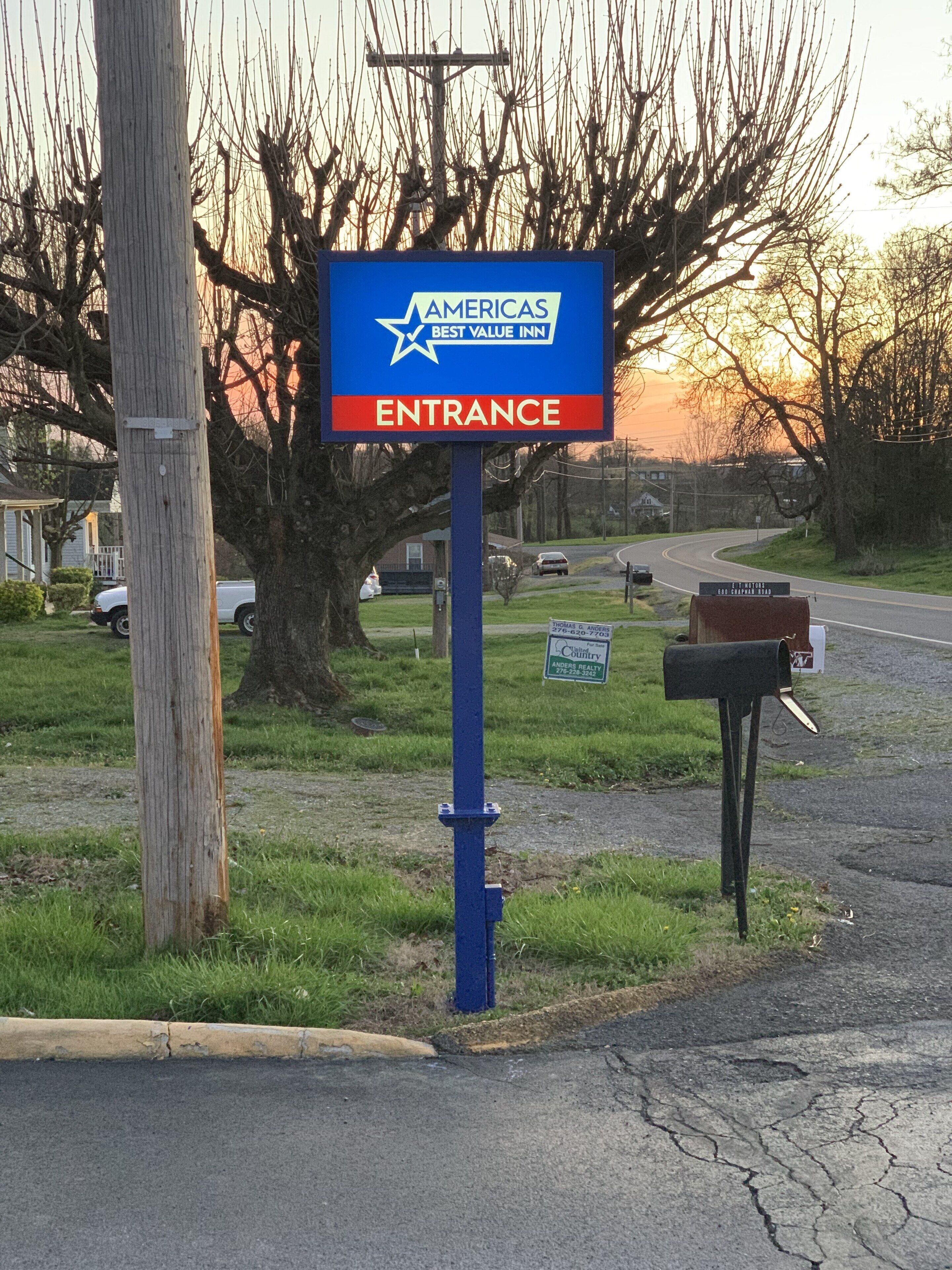 A blue sign with the text "AMERICAS BEST VALUE INN ENTRANCE" and a mailbox.