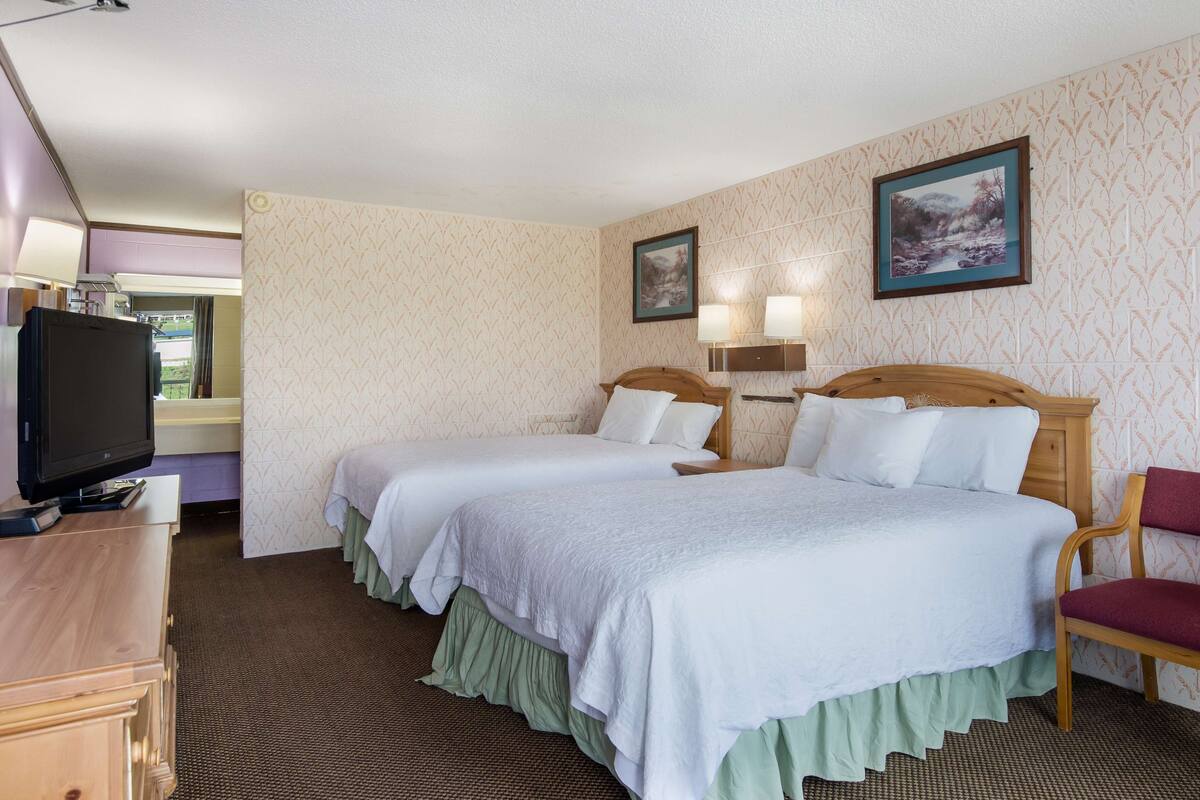 Een hotelkamer met twee bedden, een televisie, een bureau en een stoel.