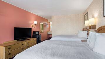 A hotel room with two beds, a television, a dresser, and a microwave.