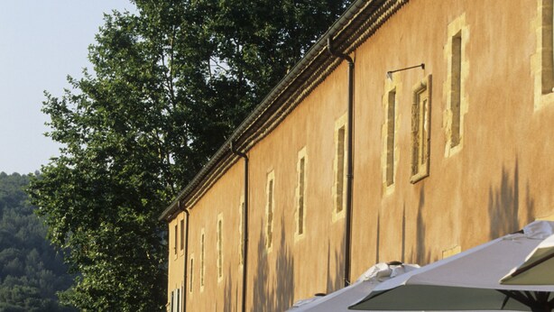Un bâtiment bordé d’une rangée de parasols, avec des haies soigneusement taillées et une pelouse bien entretenue.