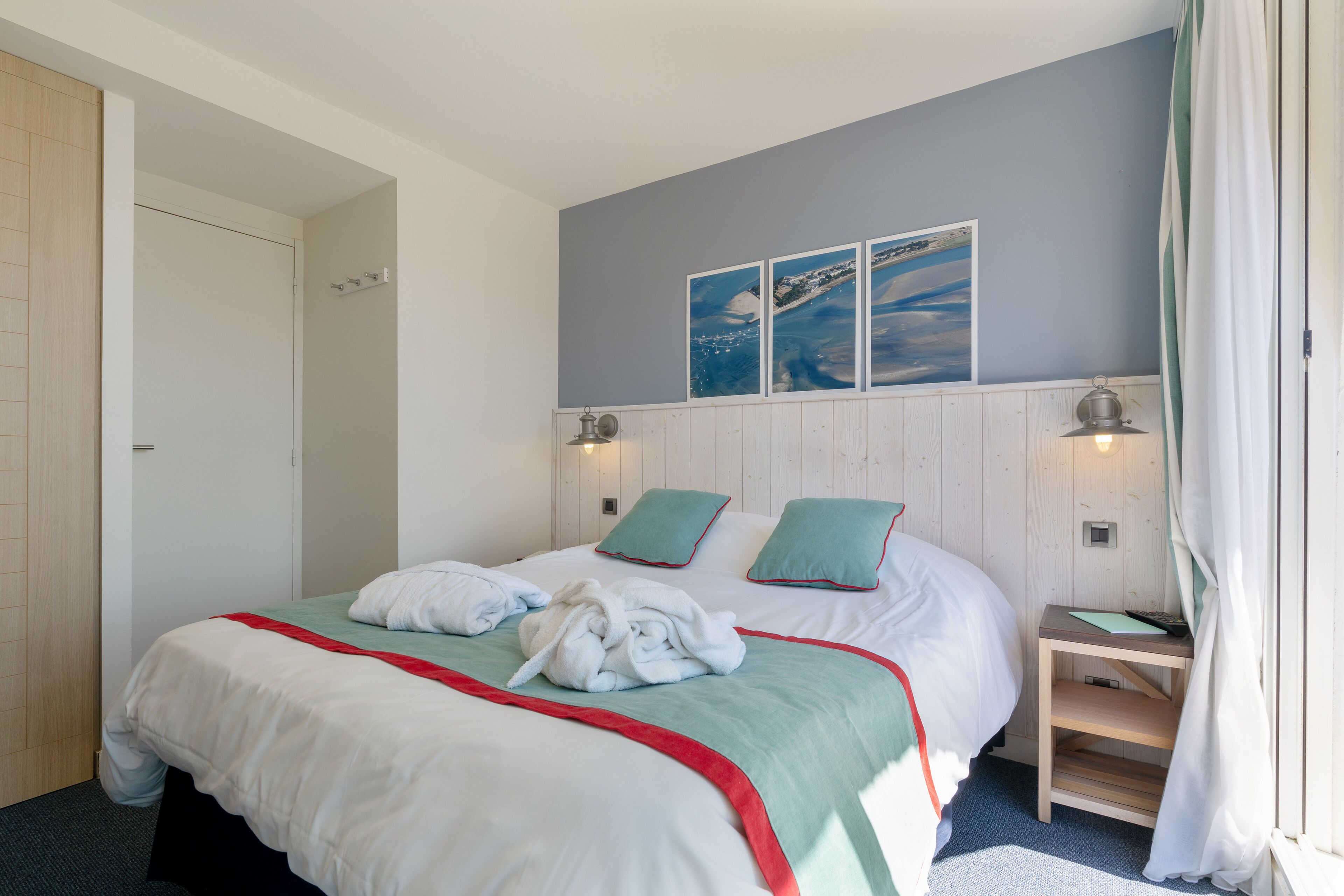 Habitación de hotel con cama, mesita de noche, armario de madera y un cuadro en la pared.