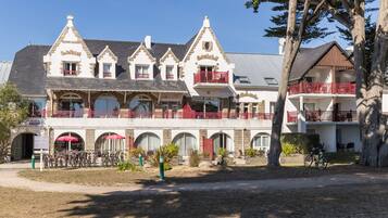 A large, multi-story building with a classic architectural style, featuring balconies with red railings and arched windows.