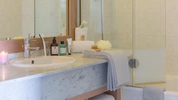 Une salle de bain avec un lavabo en marbre, un miroir, une cabine de douche en verre et un porte-serviettes.
