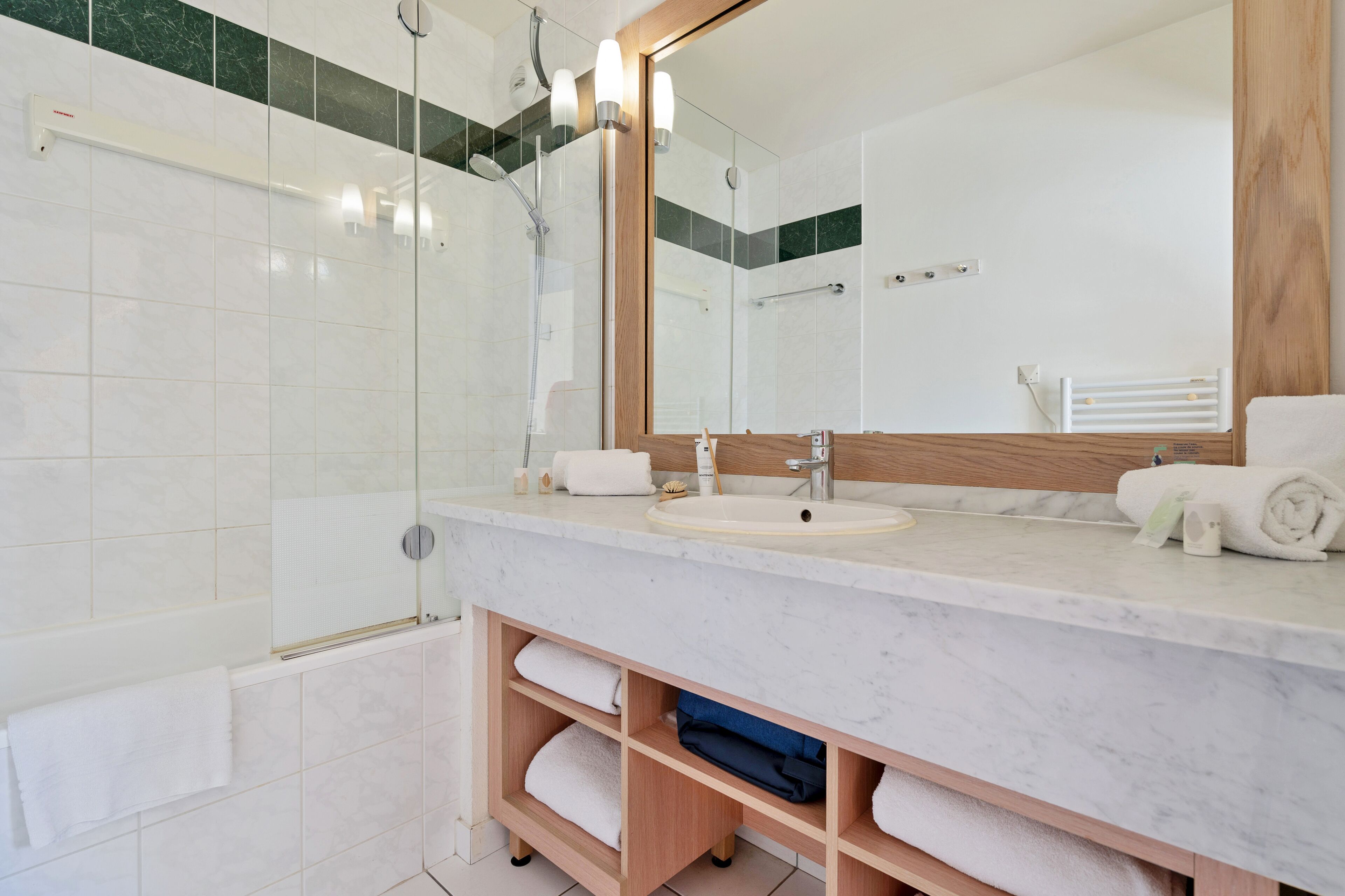 Un baño moderno con ducha envuelta en vidrio, un lavabo con espejo y toallas dobladas cuidadosamente.
