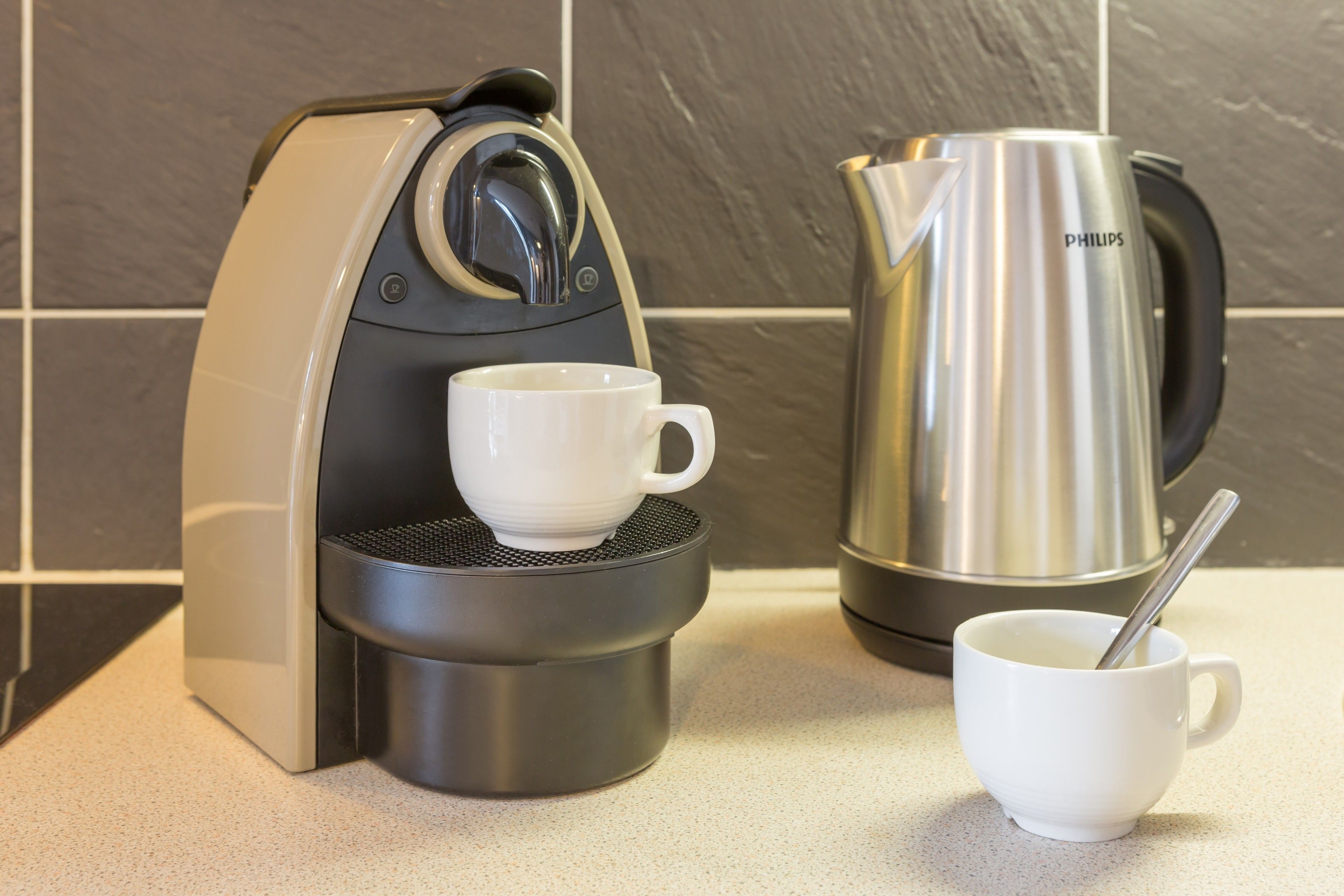 Eine Kaffeemaschine und ein Wasserkocher auf einer Arbeitsplatte.