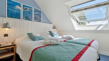 A bedroom with two beds, a skylight, and artwork on the wall.
