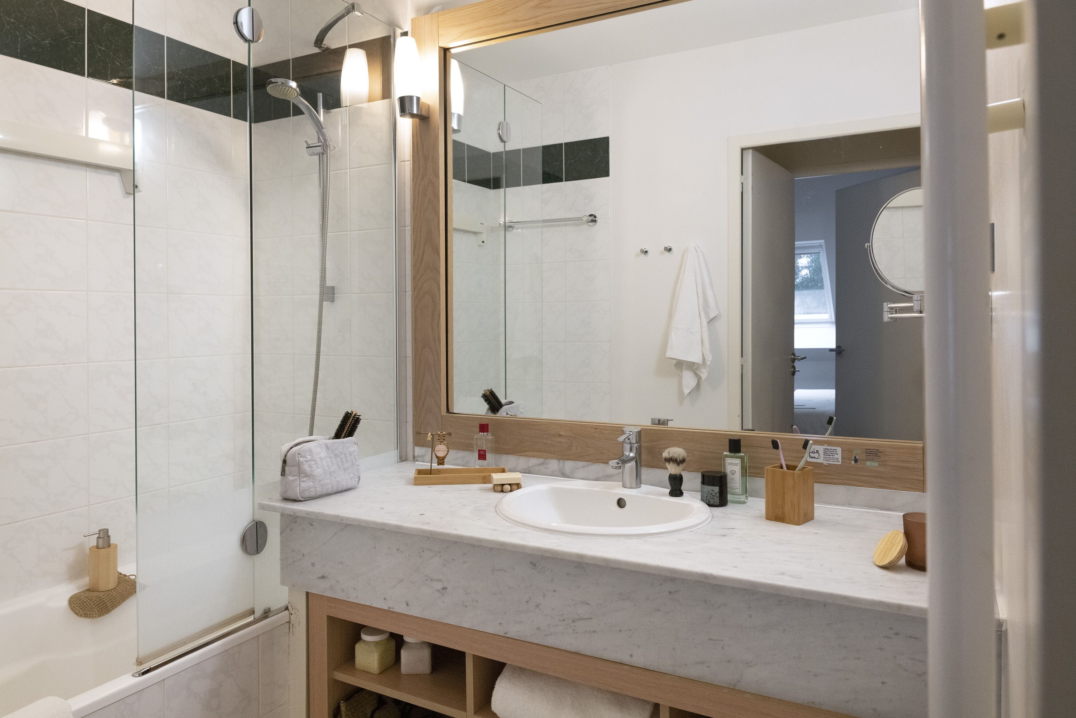 A modern bathroom with a glass-enclosed shower, a white sink, and a large mirror.