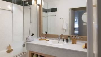 A modern bathroom with a glass-enclosed shower, a white sink, and a large mirror.