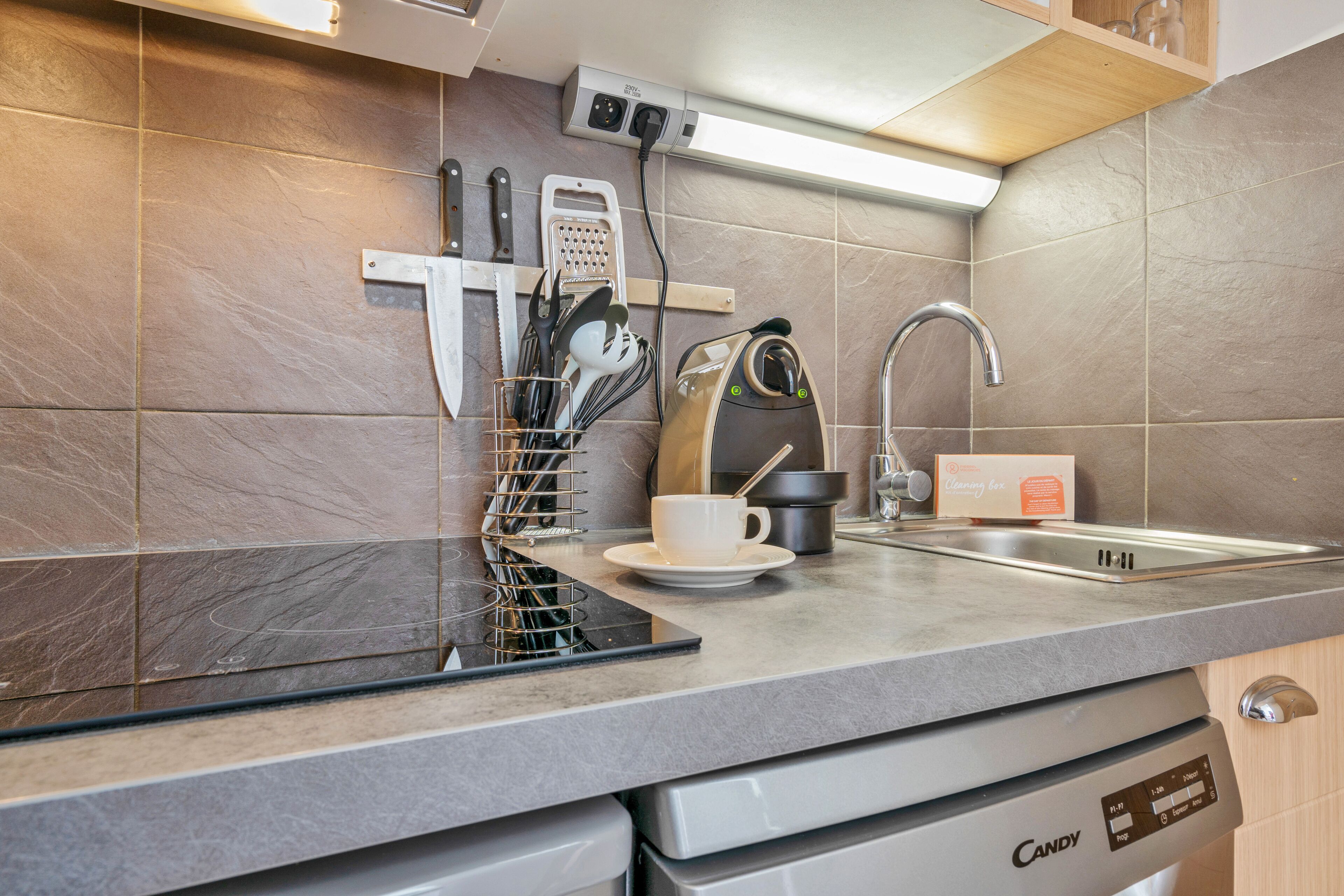 Een keuken met een modern design, voorzien van een ingebouwde vaatwasser, een roestvrijstalen spoelbak en diverse keukenaccessoires en apparaten.