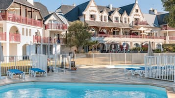 Una piscina al aire libre de temporada, sombrillas