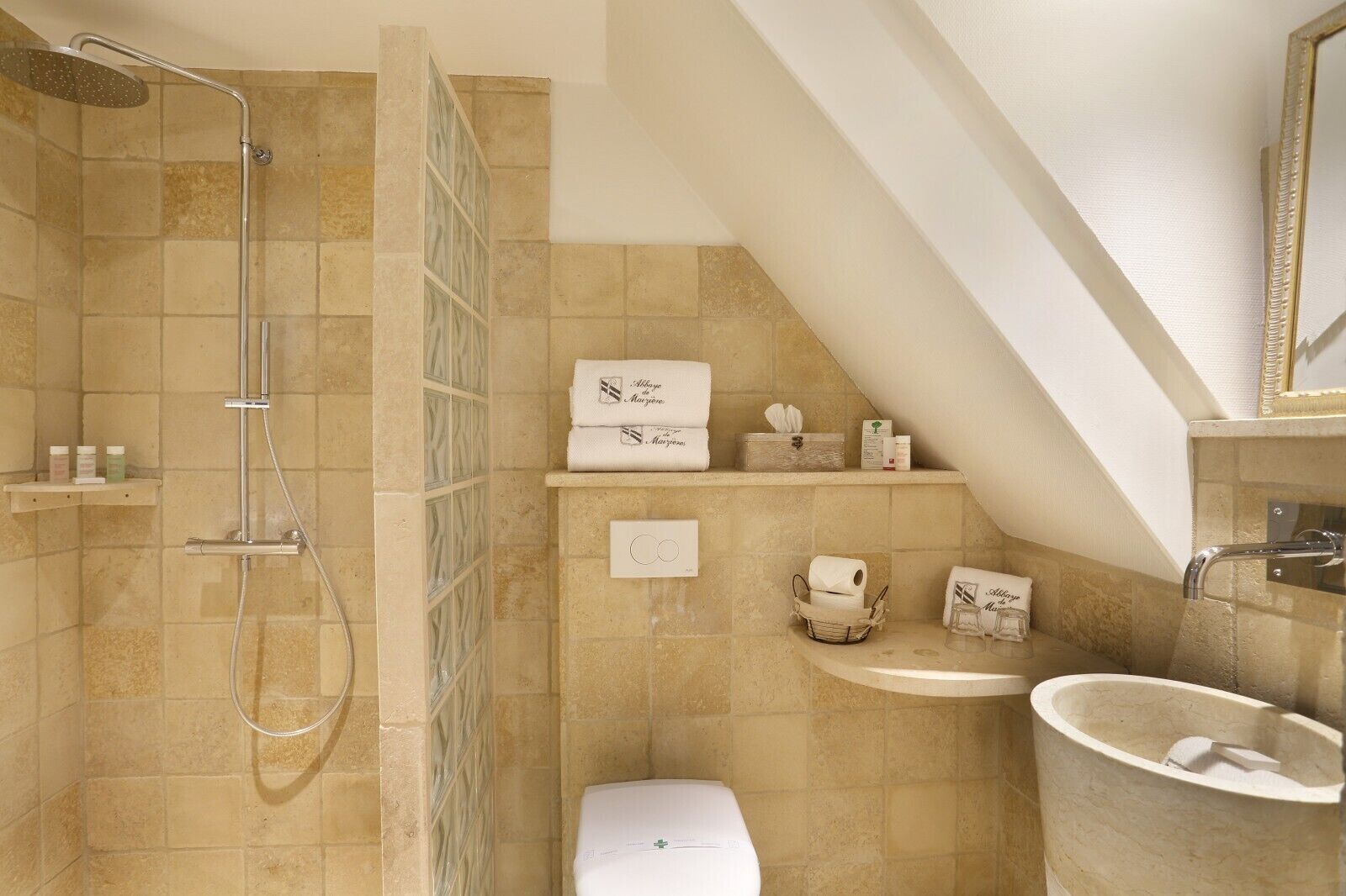 A bathroom with a shower, toilet, sink, and towel storage.
