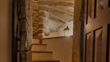 A stone staircase leading to a wooden door, with a textured ceiling and a small lantern above.