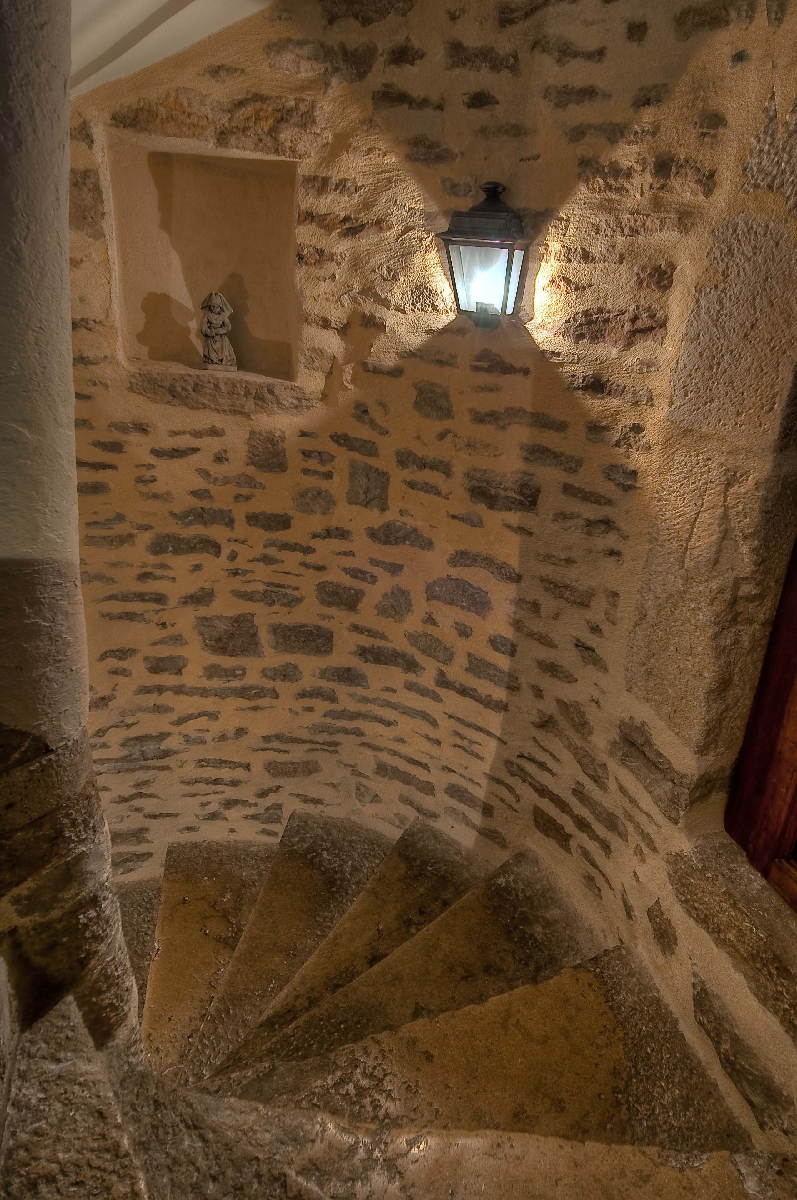 Una escalera de piedra con un farol en un hueco.