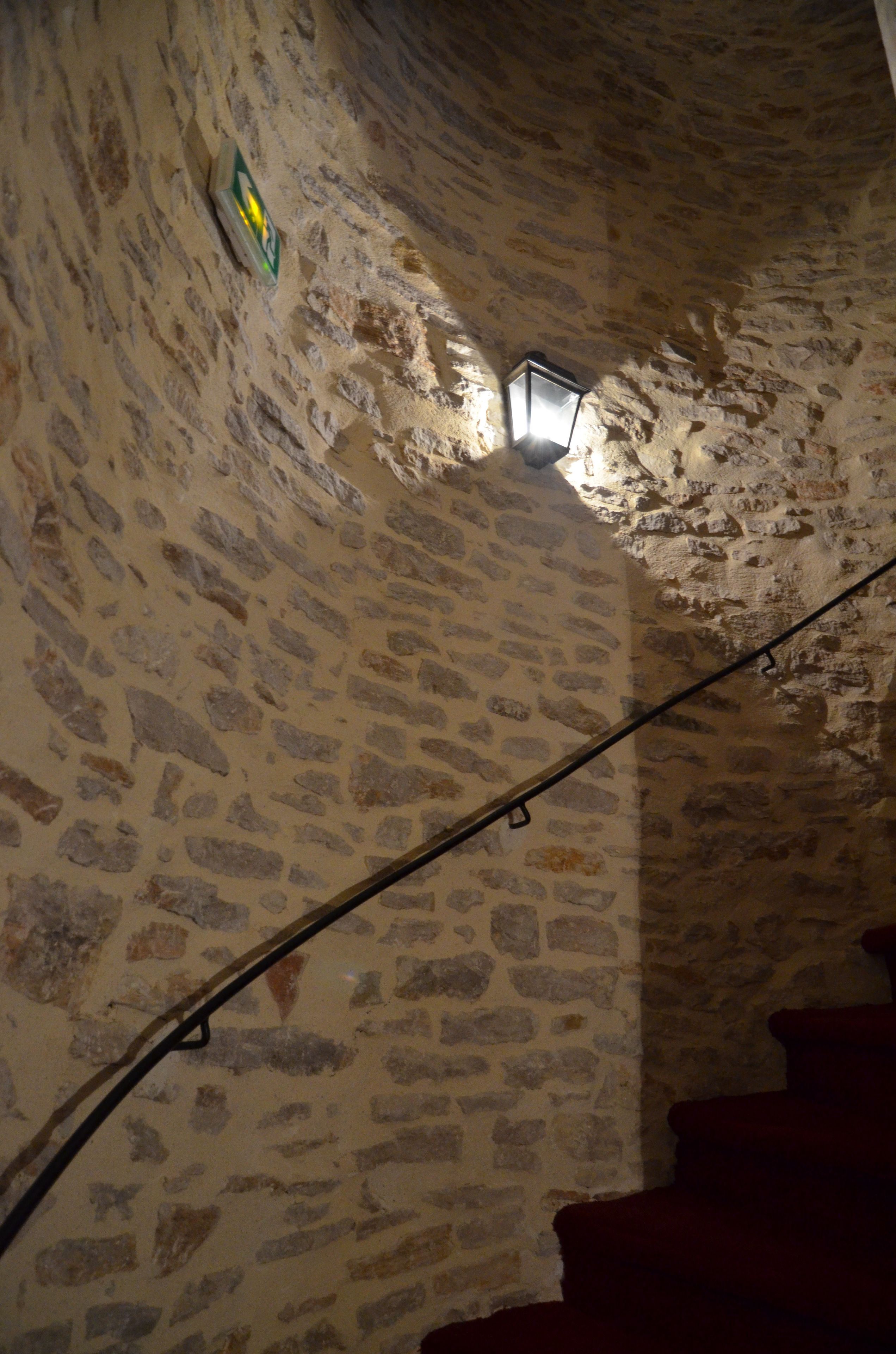 A stone wall with a lantern and a sign.