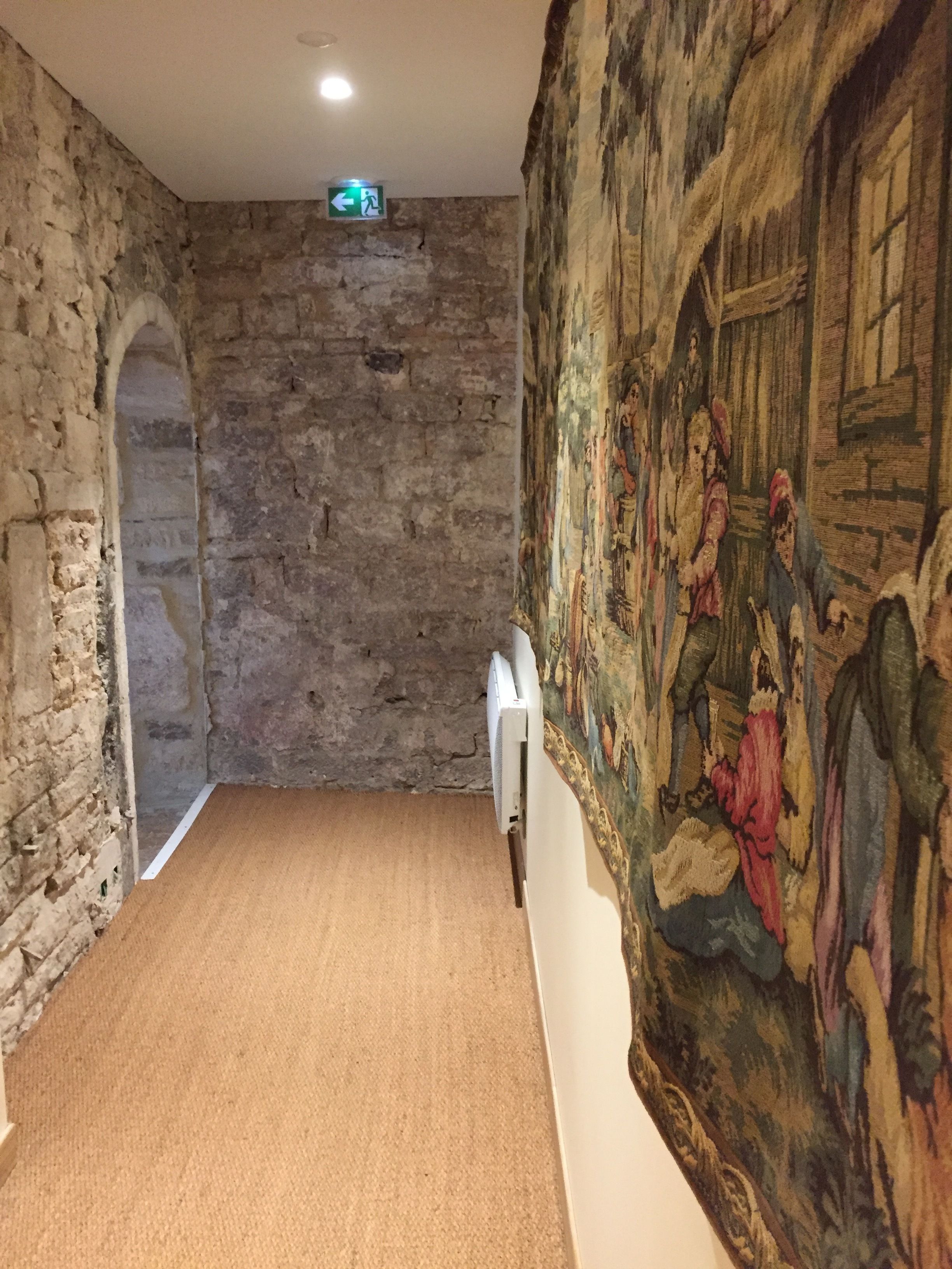 A hallway with a stone wall, a mural, and a carpeted floor.