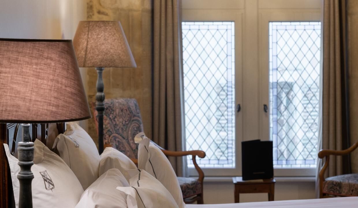 Une chambre d’hôtel avec un lit, deux chaises, une lampe et un téléviseur.