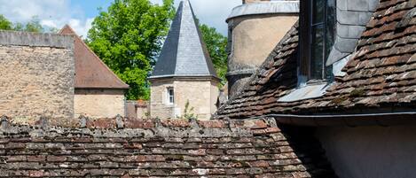A historic building with a steeply pitched roof, a visible chimney, and a small window.