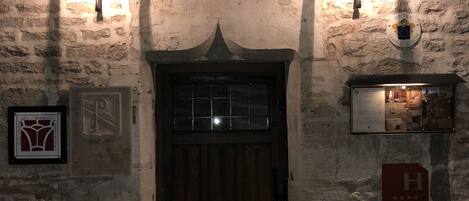 A stone building with a wooden door, two wall-mounted lights, and signs indicating a hotel and a rating.