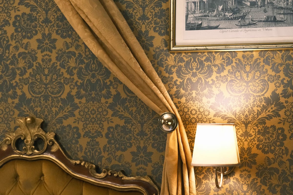 A bed with a tufted headboard, a bedside lamp, and a framed picture on the wall.
