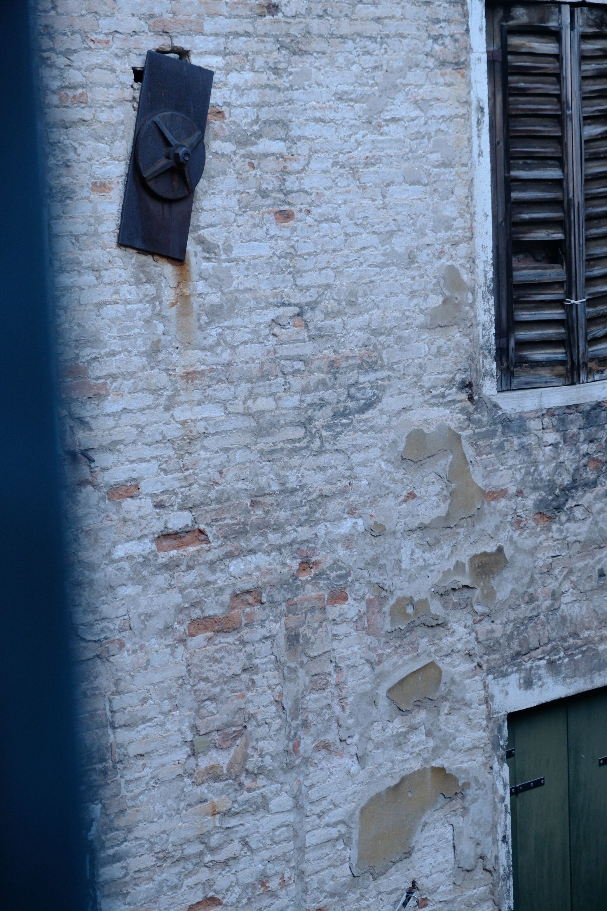 A weathered building facade with a window and a door.