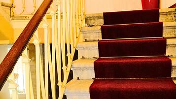 A staircase with red carpeted steps and white balustrades.