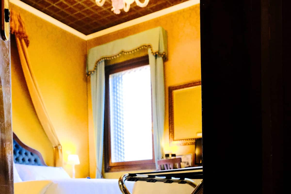 A hotel room with a bed, a desk, and a window with curtains.