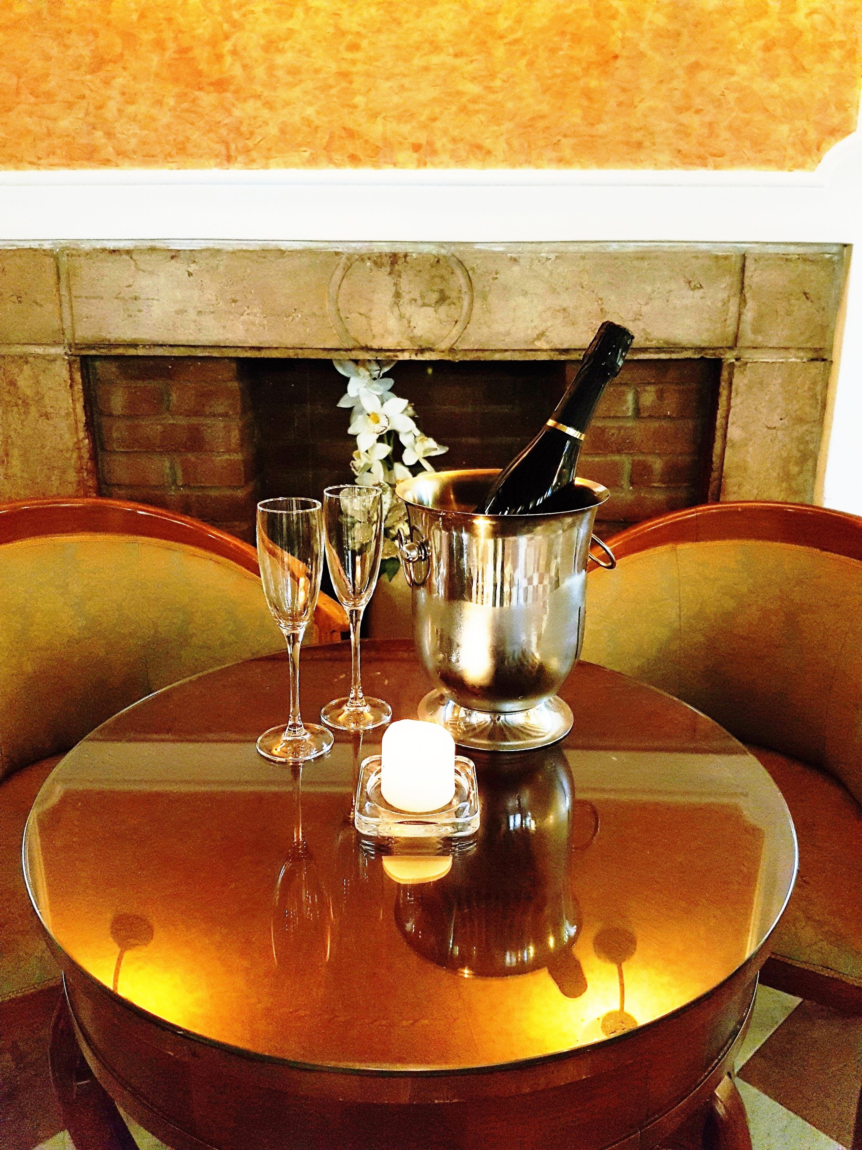 A table with a bottle of champagne, two glasses, and a candle.