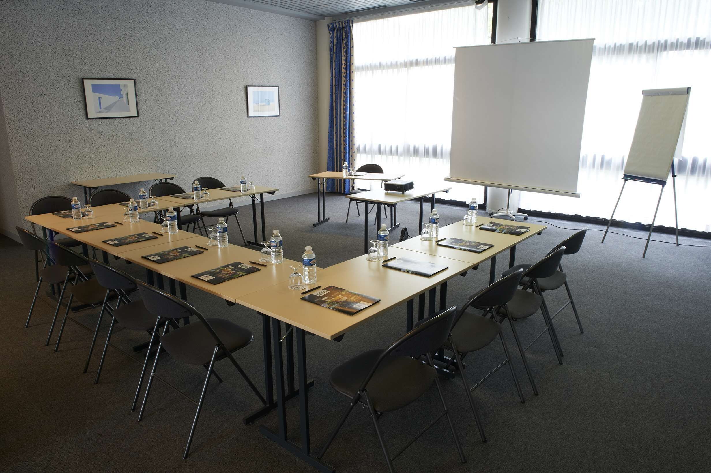 A conference room with tables, chairs, water bottles, and a whiteboard.
