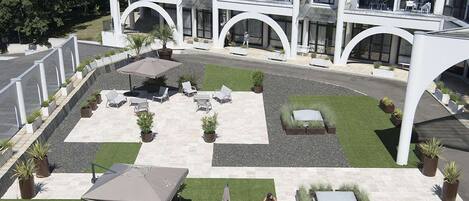 Un hotel con un patio que ofrece asientos al aire libre y una zona de piscina.